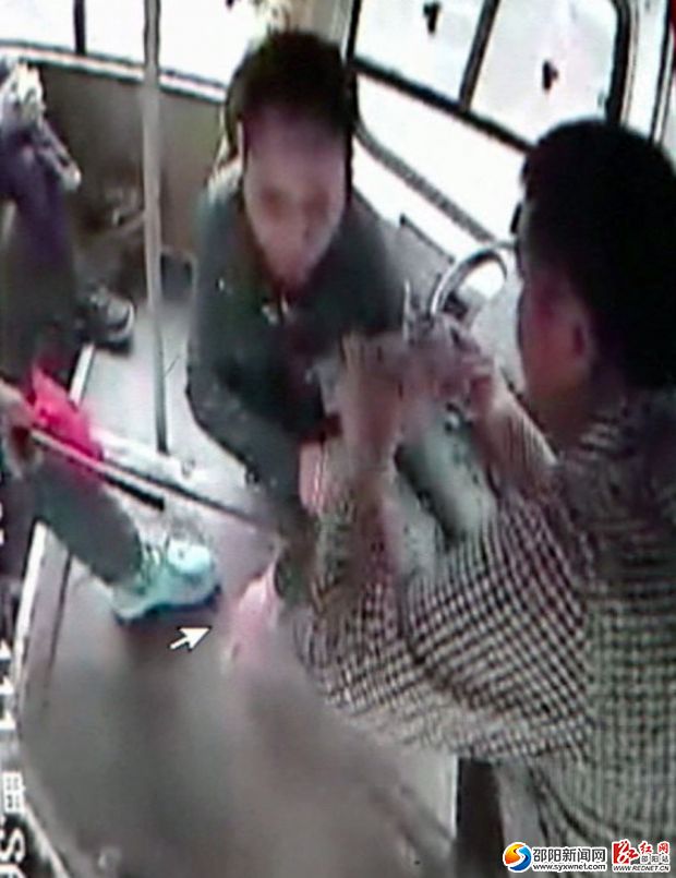 监控摄像下，一名好心的乘客正在用毛巾帮刘师傅包扎好伤口