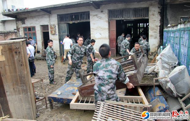 區(qū)人武部民兵正在幫助群眾清理物品。