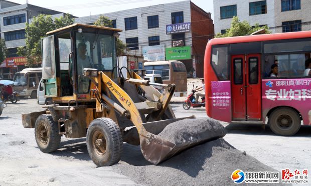 施工車(chē)輛在道路中間施工，過(guò)往車(chē)輛只能從道路兩旁緩慢通行。