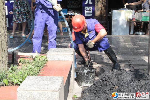 何又華準(zhǔn)備水槍沖洗下水道。