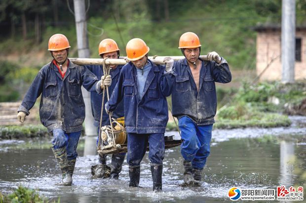 施工人員跋山涉水抬工具到現場。