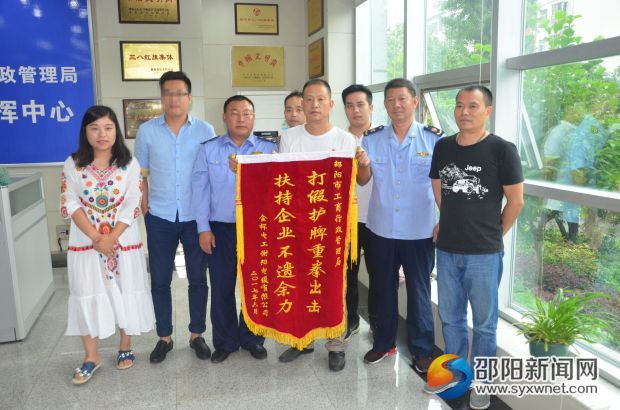 邵阳市金杯公司市场部工作人员向市工商局送上锦旗。