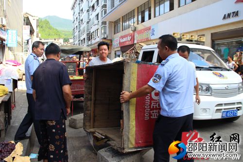 工作人員幫助門店店主清理擺出店外的攤位