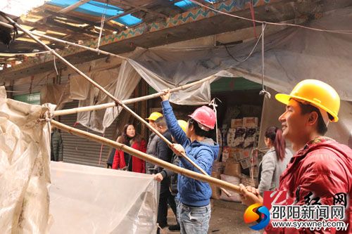 工作人員對市場內商鋪違章搭建的雨棚進行拆除