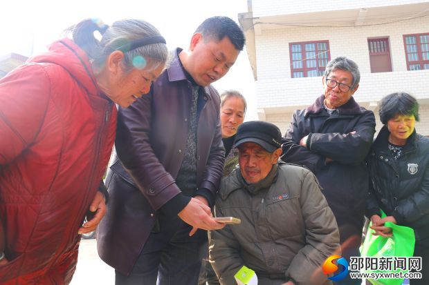 兩市塘街道黨工委書記李佑軍（左二）為貧困人口講解手機(jī)使用方法