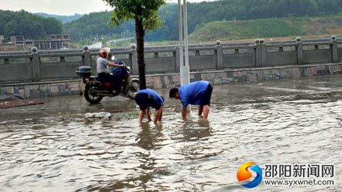 城管局執(zhí)法人員正在清理雨水井口周邊垃圾