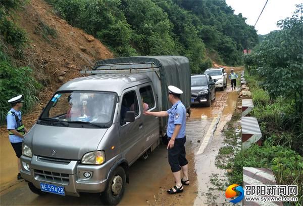 民警正在指揮車輛緩慢通過(guò)滑坡路段