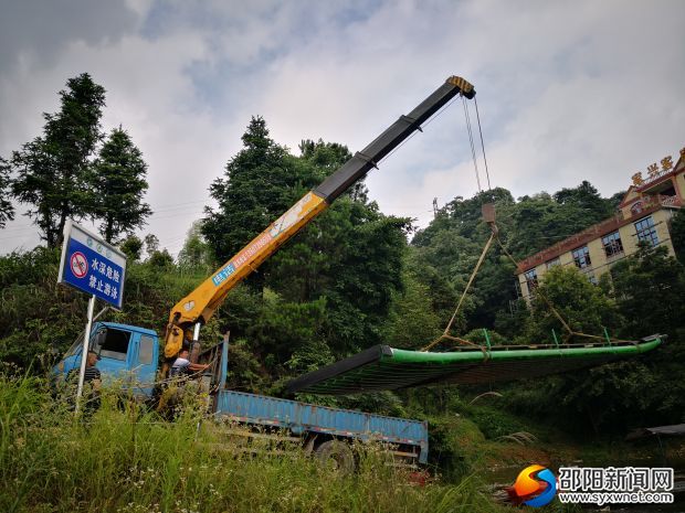 （6月27日整治行動現(xiàn)場，吊車將竹筏吊出水面。）