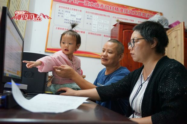 国庆前夕，吴晓芳在村部帮吉刚上传扶贫资料到电脑上。